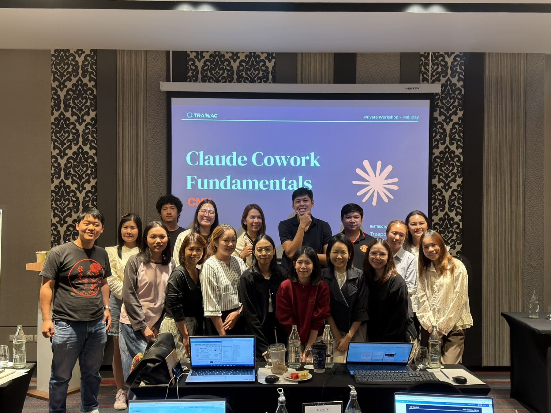 ผู้เข้าร่วมเวิร์กช็อป Claude Cowork Fundamentals ที่เชียงใหม่ ถ่ายภาพหมู่กับผู้สอน TRAINIAC หน้าสไลด์ TRAINIAC Full Day Workshop ที่ Novotel